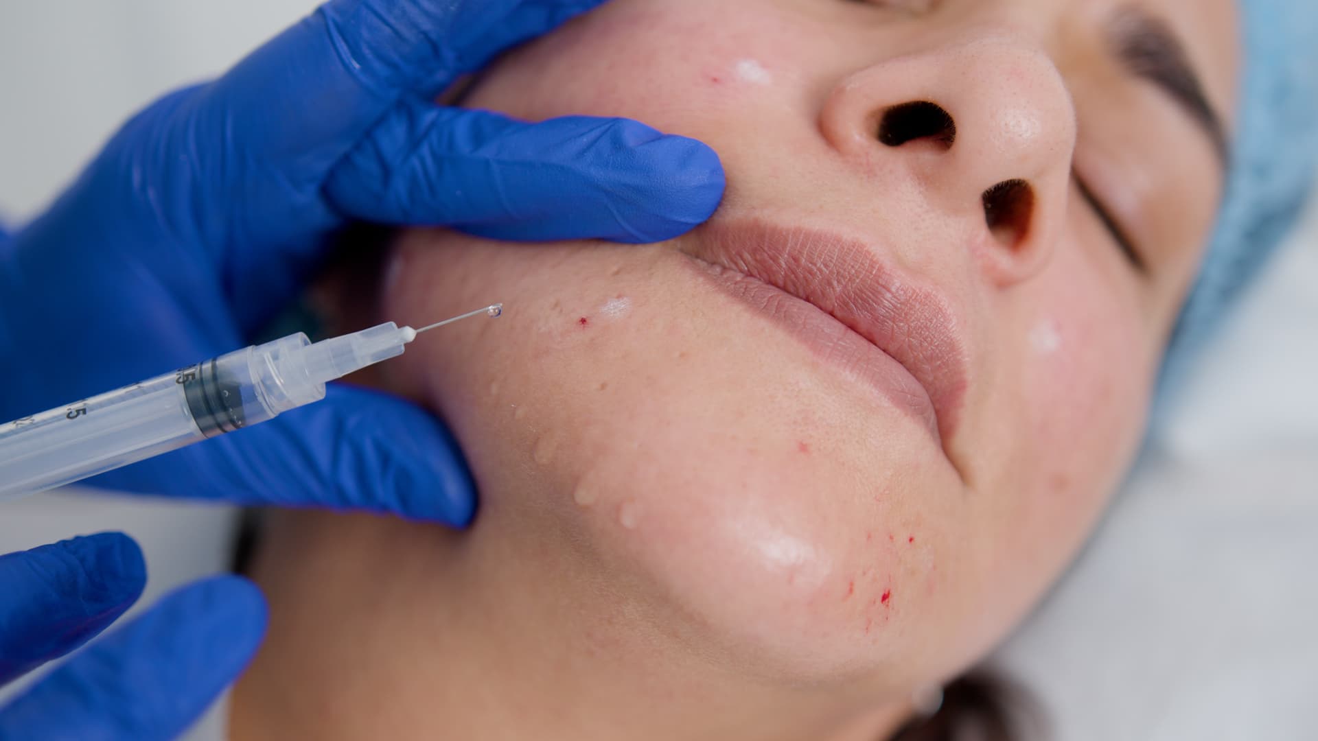 Wooden shelf with gray and olive drab green baseball caps, next to wooden clothes hanger with sweaters.